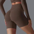 Femme en short de sport marron taille haute, mettant en valeur la silhouette. Mode fitness, vêtements de sport, style athlétique moderne.