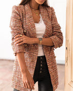 Femme portant une veste en tweed multicolore, débardeur blanc, collier doré et pantalon noir. Mode élégante, tendance automne, style chic.