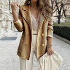 Femme élégante portant un blazer doré rayé, chemisier en dentelle blanche, pantalon blanc, tenant un sac à main beige, en ville. Mode chic et tendance.
