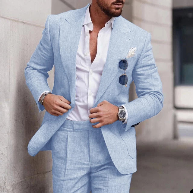 Homme en costume bleu clair élégant, chemise blanche, lunettes de soleil dans la poche, montre-bracelet argentée, style mode masculine moderne.