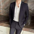 Homme en costume rayé noir et chemise blanche, posant contre un mur en marbre. Mode masculine élégante, tenue professionnelle, style moderne.