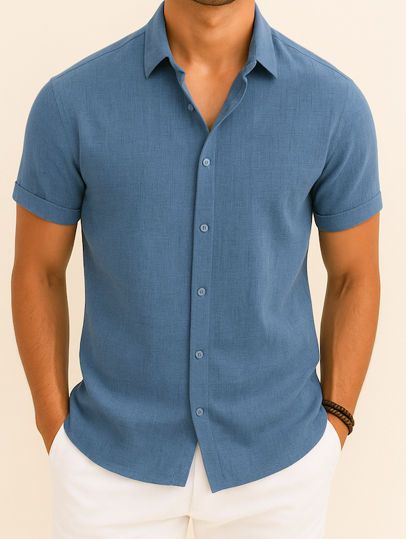 Homme portant une chemise bleue à manches courtes, élégante et décontractée, avec un pantalon blanc. Mode masculine estivale, style moderne.