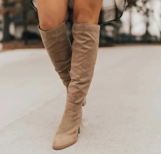 Bottes hautes en daim beige sur fond urbain flou, mode automne-hiver, style élégant et tendance, chaussures femme, look chic et moderne.