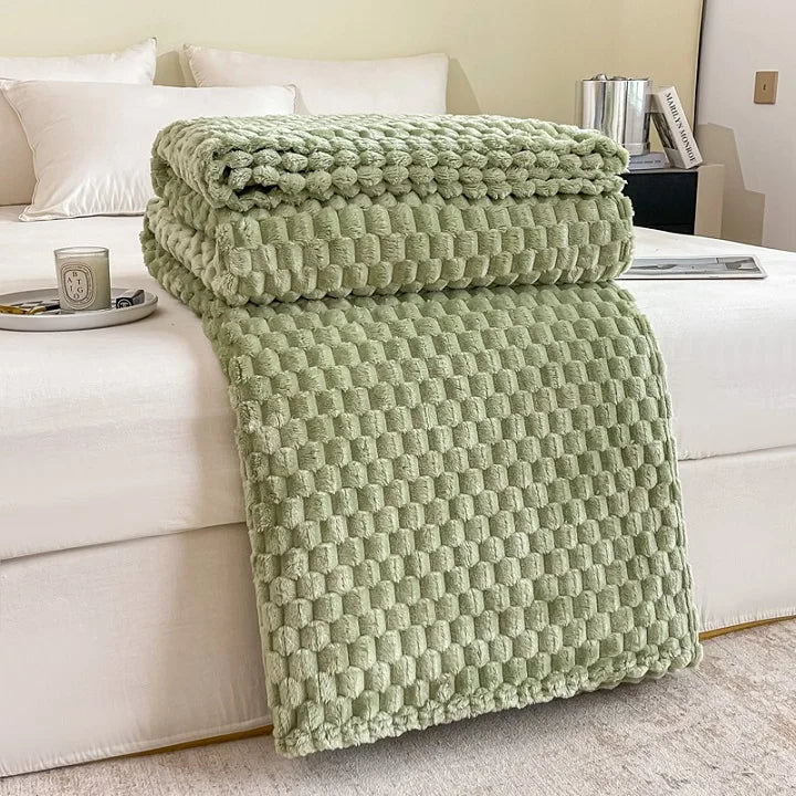 Couverture en peluche verte sur un lit blanc, avec oreillers et tasse à café. Décoration intérieure moderne, chambre confortable et élégante.