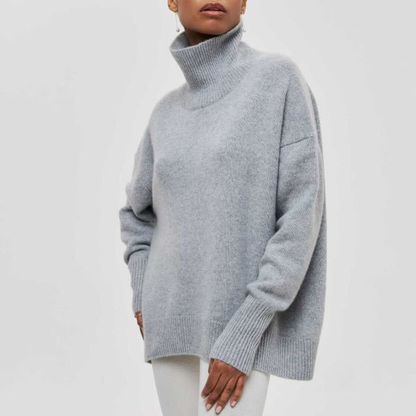 Femme portant un pull en laine gris à col roulé, manches longues, style décontracté. Mode automne-hiver, vêtement chaud et confortable.