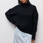 Femme portant un pull noir à col roulé et une jupe en jean clair, mode automne-hiver, style décontracté et élégant.