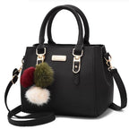 Sac à main noir élégant avec bandoulière, décoré de pompons colorés. Accessoire mode femme, cuir synthétique, style chic et moderne.