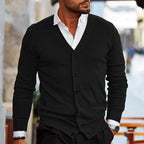 Homme portant un cardigan noir élégant sur chemise blanche, style urbain chic, mode masculine moderne, rue en arrière-plan floue.