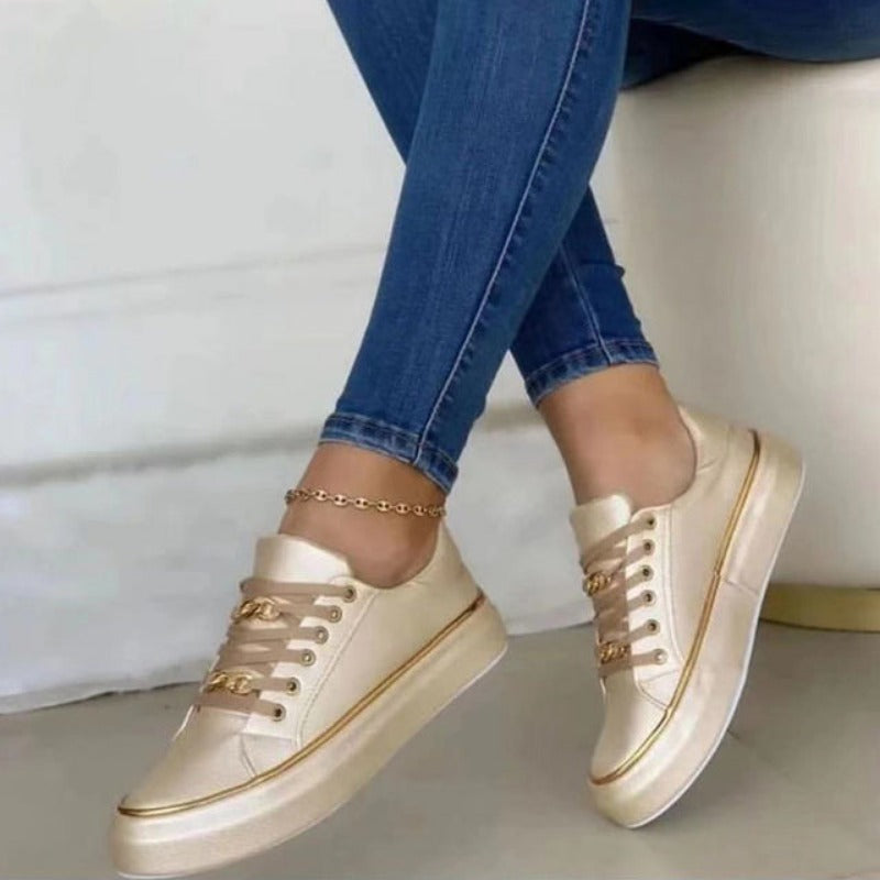 Chaussures dorées élégantes pour femme, portées avec un jean slim. Sneakers tendance, mode féminine, style décontracté chic.