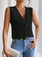 Femme portant un haut noir sans manches avec un col en V, un jean bleu, un collier doré et un sac blanc matelassé. Mode élégante et chic.