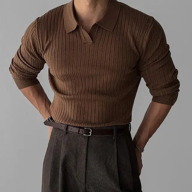 Homme portant un pull marron côtelé à col polo, manches retroussées, avec un pantalon gris foncé. Mode masculine élégante et décontractée.