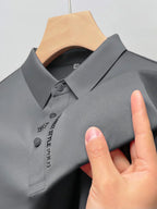 Chemise polo grise élégante sur cintre, tissu texturé, boutons noirs, logo brodé, mode masculine, vêtement tendance, style décontracté chic.