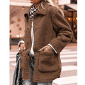 Femme portant un manteau en fausse fourrure marron, style décontracté, avec écharpe à pois, sur fond urbain. Mode automne-hiver tendance.