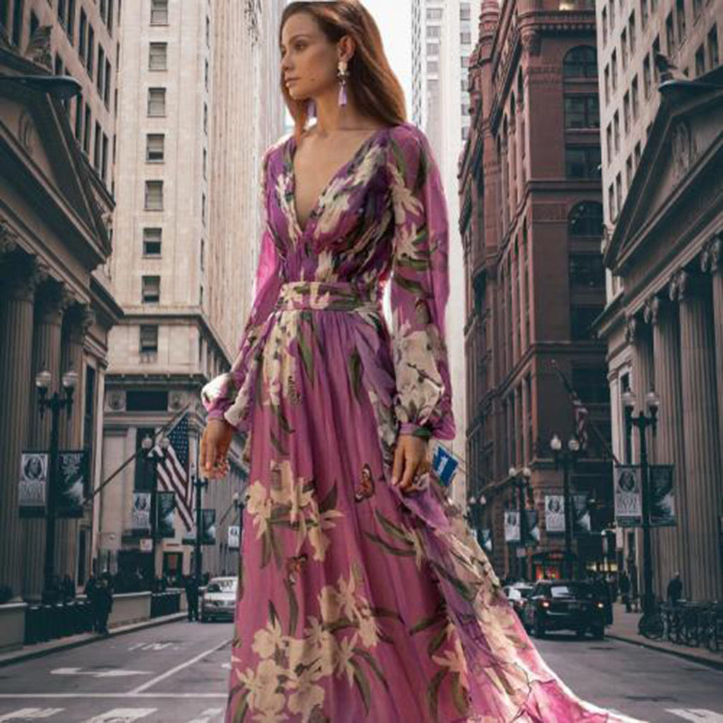 Robe longue violette à motifs floraux portée par une femme dans une rue urbaine, entourée de bâtiments historiques, style élégant et moderne.