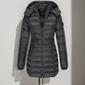Doudoune noire longue avec capuche amovible, fermeture éclair frontale, design matelassé, idéale pour l'hiver et les températures froides.