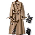 Trench-coat beige élégant avec doublure à carreaux, ceinture assortie, sac à main noir texturé et escarpins noirs. Mode automne chic.