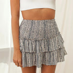 Femme portant une jupe courte à volants imprimée, taille haute, avec un haut blanc côtelé. Mode estivale, style décontracté, tendance féminine.