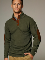 Homme portant un pull vert à col montant avec coudières marron, style décontracté. Mode masculine automne-hiver, tendance élégante et confortable.