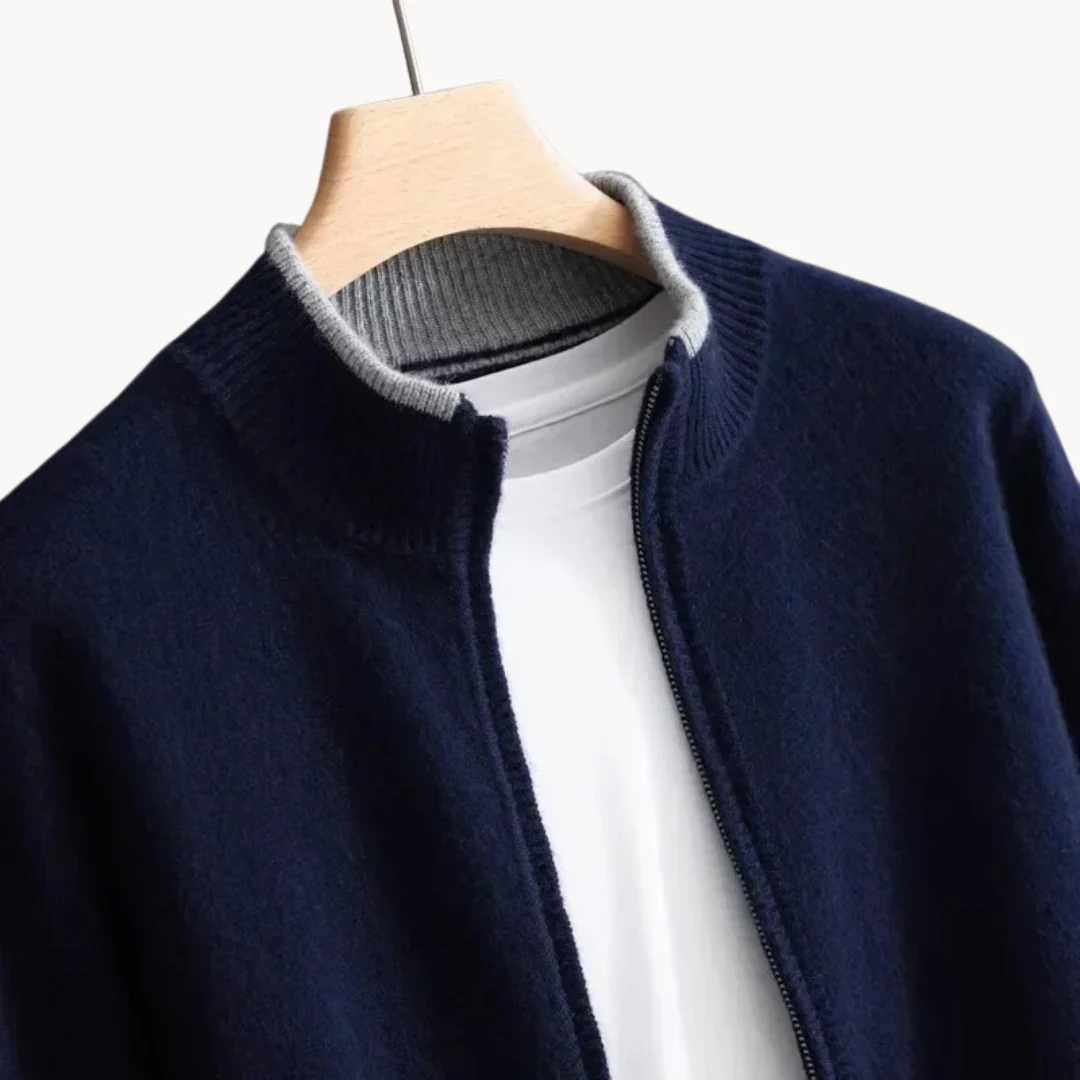 Veste en laine bleu marine avec col gris, fermée par un zip, suspendue sur un cintre en bois, sur fond blanc. Mode homme élégante et moderne.
