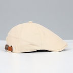 Casquette plate beige en coton avec sangle réglable en cuir marron, style rétro. Accessoire de mode élégant pour homme et femme.