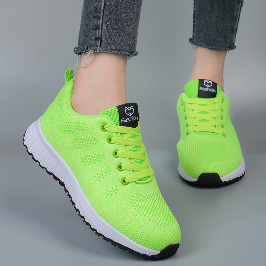 Chaussures de sport vert fluo pour femme, semelle blanche, lacets assortis, portées avec un jean. Sneakers tendance et confortables.
