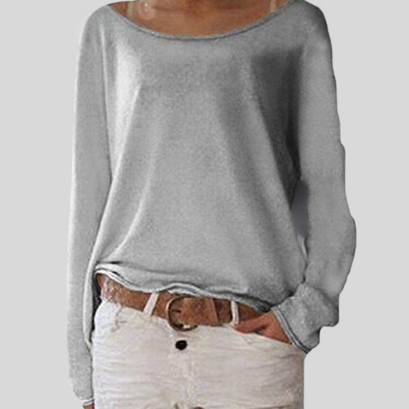 Femme portant un pull gris ample à col bateau et un short blanc, ceinture marron. Mode décontractée, tenue estivale élégante et confortable.