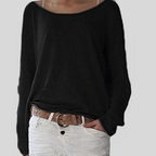 Femme portant un pull noir ample avec un col bateau, associé à un pantalon blanc et une ceinture marron. Mode décontractée élégante.