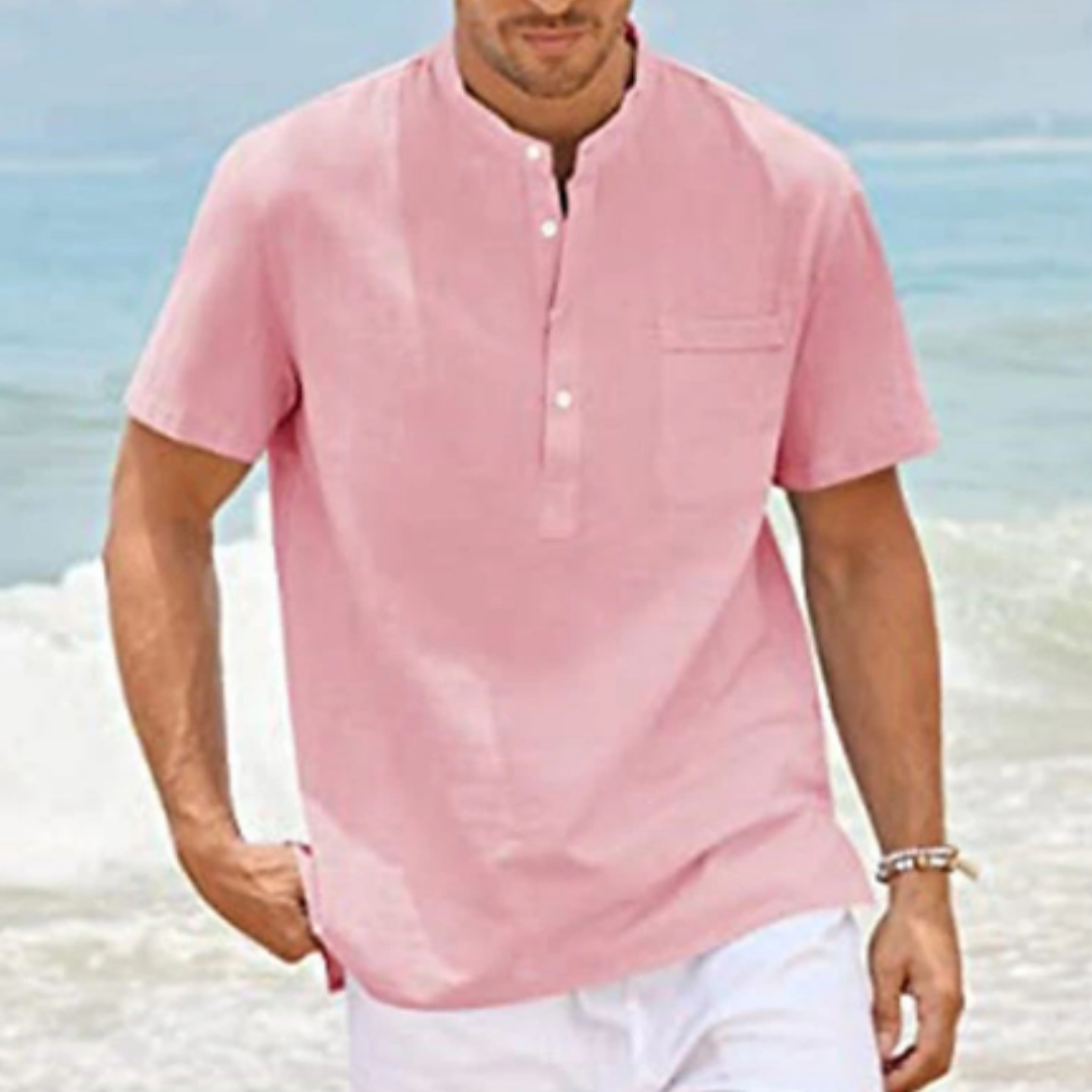 Homme en chemise rose à col mao, manches courtes, marchant sur la plage. Mode estivale, tenue décontractée, bord de mer, style tendance.