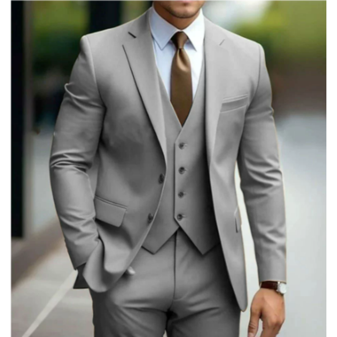 Homme en costume gris élégant avec cravate marron, posant en extérieur. Mode masculine, tenue formelle, style professionnel.