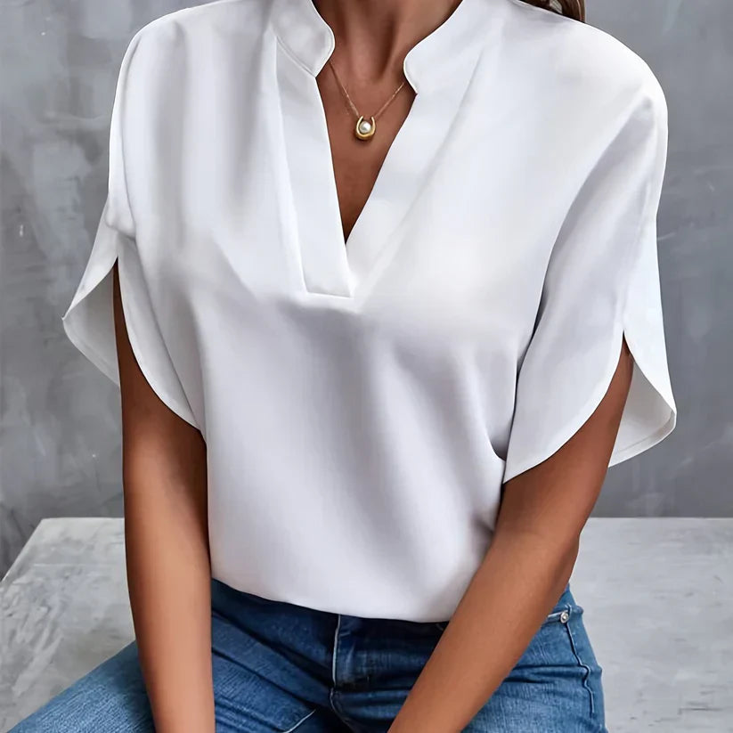 Blouse blanche élégante à manches courtes, col en V, portée avec un jean bleu. Mode féminine chic, tenue décontractée, style moderne.
