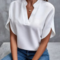 Blouse blanche élégante à manches courtes, col en V, portée avec un jean bleu. Mode féminine chic, tenue décontractée, style moderne.