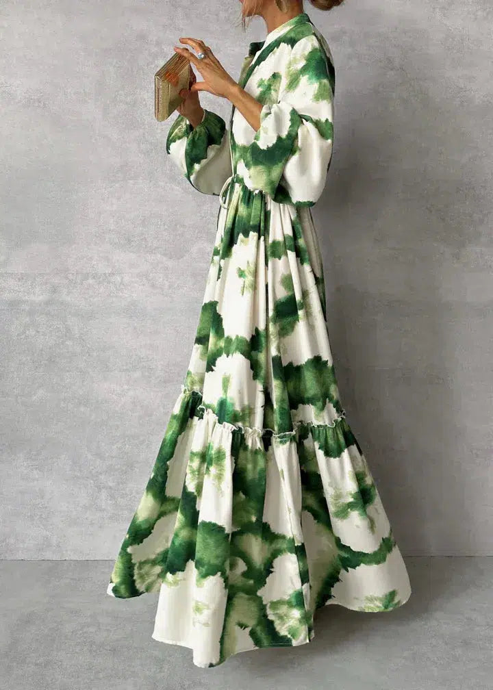 Robe longue à motifs tie-dye vert et blanc, manches bouffantes, ceinture à la taille, femme tenant un livre, style bohème chic.