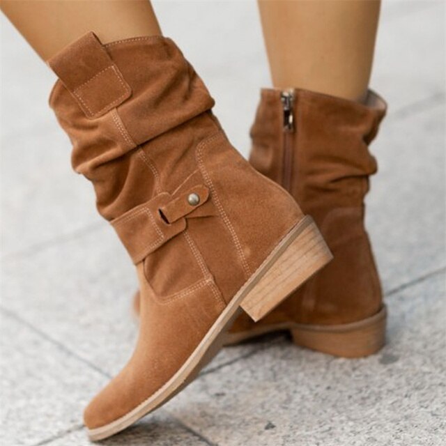 Bottes en daim marron clair pour femme avec talon bas, fermeture éclair latérale et boucle décorative, sur fond de sol en pierre grise.
