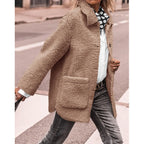 Veste en laine bouclée beige pour femme, style automne-hiver, avec poches avant, portée sur chemise blanche et jean, mode urbaine chic.