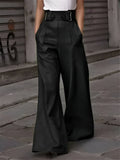 Pantalon large noir femme, taille haute avec ceinture, style urbain chic, rue pavée en arrière-plan, mode élégante et moderne.