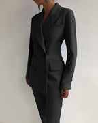 Costume noir élégant pour femme, style moderne et professionnel, avec veste à double boutonnage et pantalon assorti, mode féminine chic.