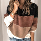 Femme portant un pull tricolore en laine, noir, marron et beige, avec des manches longues, associée à un jean. Mode automne-hiver tendance.