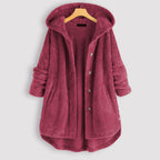Manteau en laine polaire rose avec capuche, boutons et poches, suspendu sur un cintre en bois. Vêtement d'hiver chaud et confortable.
