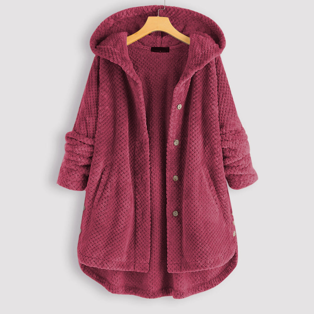 Manteau en laine polaire rose avec capuche, boutons et poches, suspendu sur un cintre en bois. Vêtement d'hiver chaud et confortable.