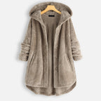 Manteau en fausse fourrure beige avec capuche, boutons et poches, suspendu sur un cintre en bois. Vêtement d'hiver chaud et élégant.