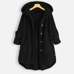 Veste en laine noire à capuche, boutons en métal, manches longues retroussées, style décontracté, suspendue sur un cintre en bois.