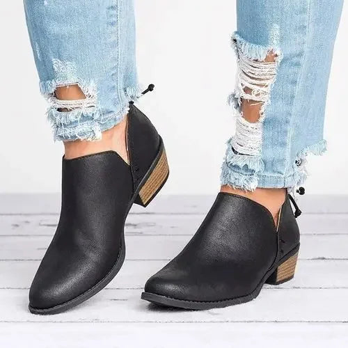 Chaussures noires en cuir pour femme avec talons bas, portées avec un jean déchiré bleu clair. Mode tendance, style décontracté.
