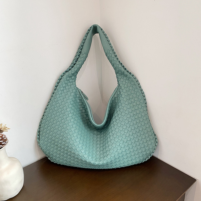 Sac à main tissé vert menthe sur une table en bois, design moderne et élégant, parfait pour la mode féminine. Accessoire tendance et chic.
