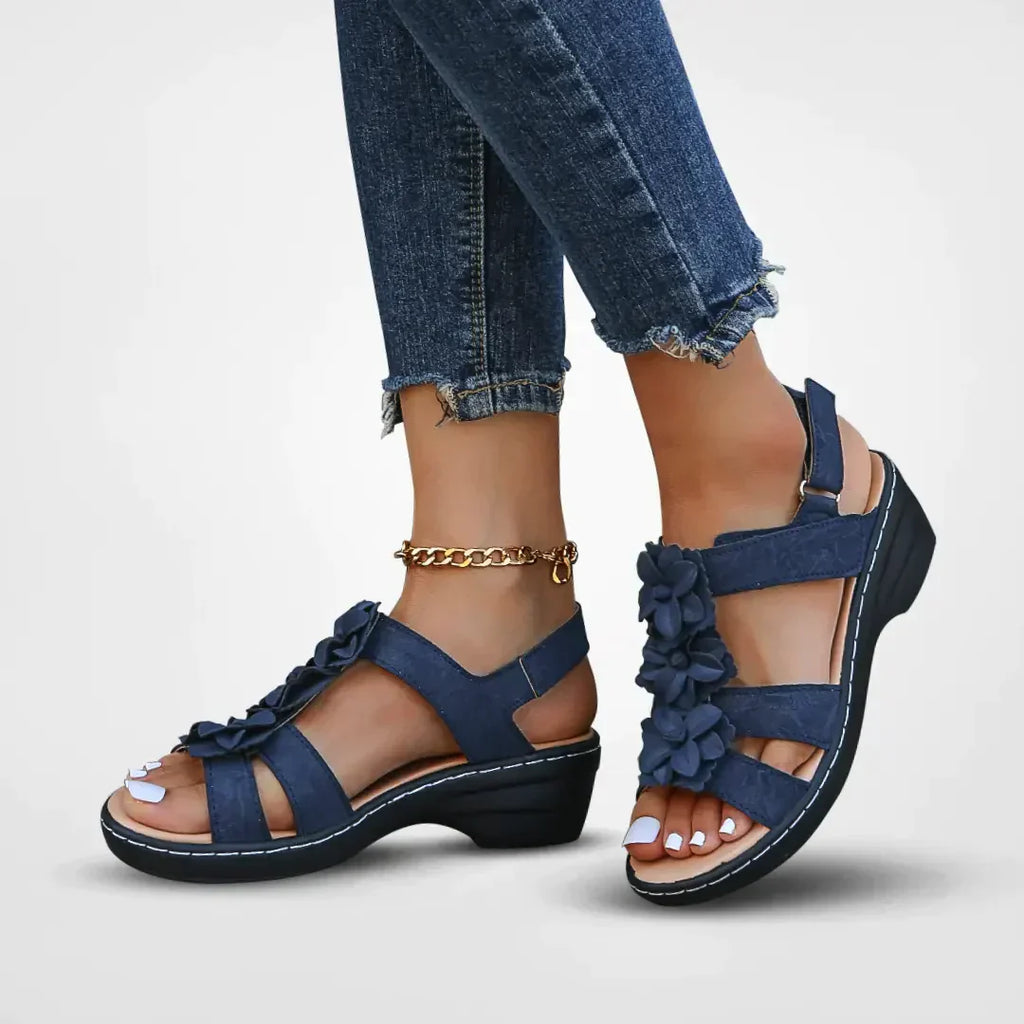 Sandales bleues à talons bas avec fleurs décoratives, portées avec un jean effiloché. Chaussures d'été élégantes pour femmes.