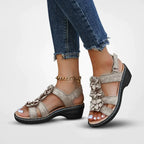 Sandales beiges à talon compensé avec fleurs décoratives, portées avec un jean effiloché. Chaussures d'été élégantes pour femmes.