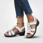 Sandales blanches à talons compensés avec fleurs, portées avec un jean déchiré. Chaussures d'été élégantes pour femmes, mode décontractée.