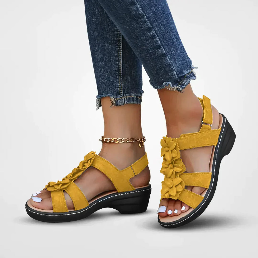 Sandales jaunes à fleurs pour femme, talon compensé, portées avec un jean déchiré. Chaussures d'été élégantes et confortables.