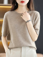 Femme portant un pull en cachemire beige, montre élégante et collier doré, mode automne-hiver, style chic et décontracté.