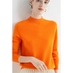 Femme portant un pull orange vif à col montant, manches longues, posant contre un fond blanc. Mode automne, style élégant et moderne.