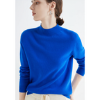 Femme portant un pull bleu vif, manches longues, col rond, avec des boucles d'oreilles argentées, posant de profil. Mode élégante et moderne.